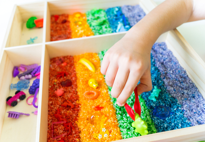 kid_playing_sensory_box_with_colored_rice