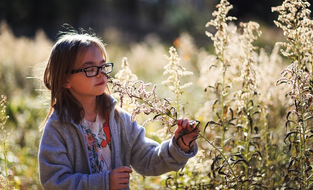 girl with glasses smelling flower